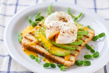 Breakfast with poached egg toast with avocado, vegetarian food.Healthy sandwich with avocado and poached eggs.