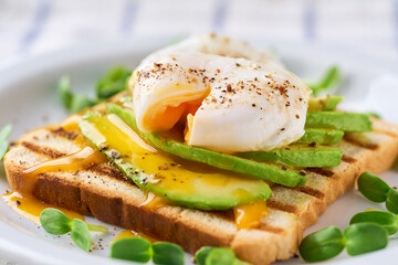 Breakfast with poached egg toast with avocado, vegetarian food.Healthy sandwich with avocado and poached eggs.