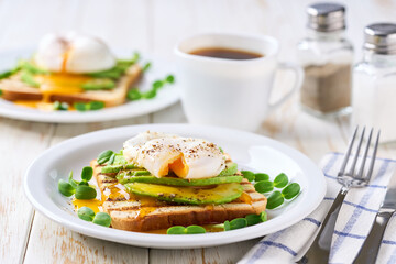 Breakfast with poached egg toast with avocado, vegetarian food.Healthy sandwich with avocado and poached eggs.