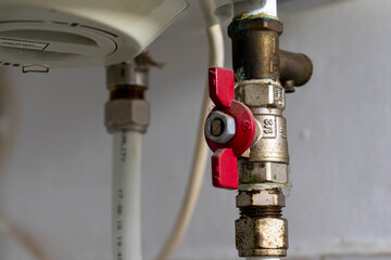 Red valve on  electric water heating boiler close up shot.
