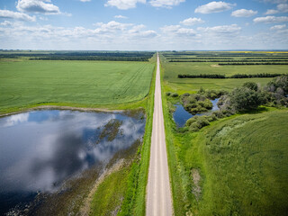 Road runs through a field with a body of water on one side