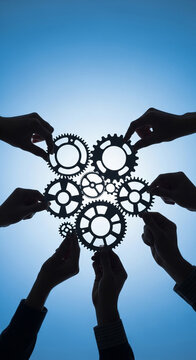 Hands connecting metal gears against a bright blue sky, symbolizing teamwork and synergy.
