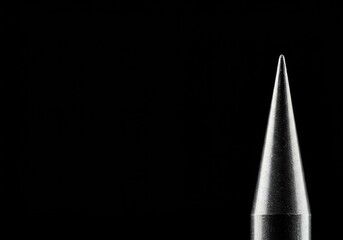 A sharp metallic spike positioned against a plain background, emphasizing danger, strength, and precision engineering. The conical tip catches the light ,close up ,cone ,end