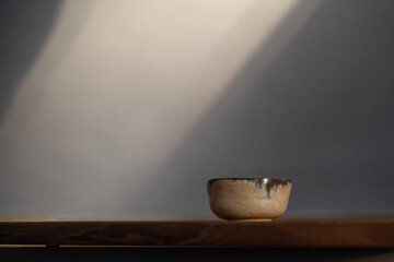 Handmade ceramic cup with blue glaze stands on a wooden tray, tea party theme, free space for text