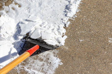 Using snow scraper or ice chopper to remove packed snow from sidewalk. Winter weather safety, home maintenance and snowstorm concept. © JJ Gouin