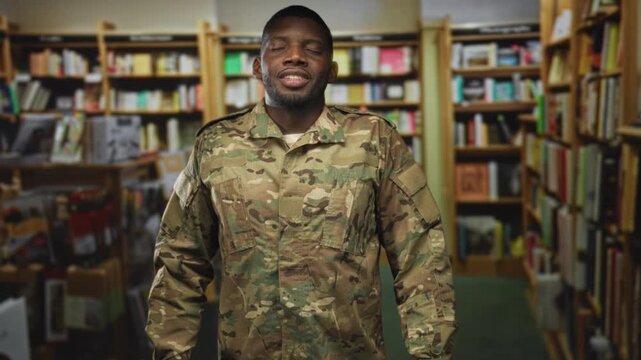 Young soldier man in camouflage uniform standing with eyes closed and relaxed posture in a library building; quiet reflection serenity.