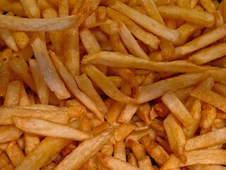 A full-frame, close-up view of a large pile of golden-brown, crispy French fries.