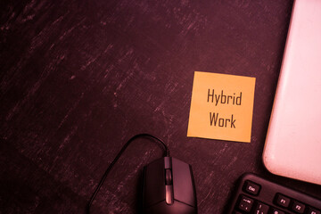 Hybrid Work concept on desk background, keyboard and mouse, laptop on a black table, sticky notes with text
