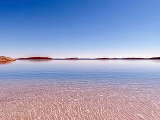 A serene landscape featuring a vast, calm lake with clear, shallow water revealing a sandy bottom with rippling patterns. Distant islands with sparse trees dot