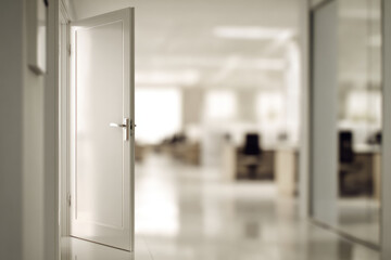 Open white door in modern office hallway with bright natural light, blurred background, and empty workspace, creating welcoming and optimistic atmosphere