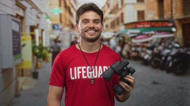 Young man lifeguard holding binoculars on street, smiling with tongue out and whistle on necklace; playful.