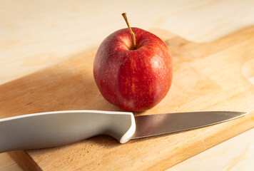 Single Ripe Red Apple Centered on a Wooden Cutting Board Next to a Modern Kitchen Knife