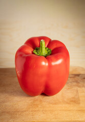 Vertical Close-up of a Single Ripe Red Bell Pepper on a Wooden Cutting Board