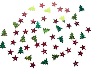 Christmas holiday confetti background with scattered glittery red stars and green trees on a neutral soft gray surface, top view with copy space.