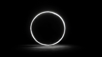 A bright white glowing ring with a subtle sparkle effect, standing upright on a dark, textured surface. The background is completely black, creating a dramatic