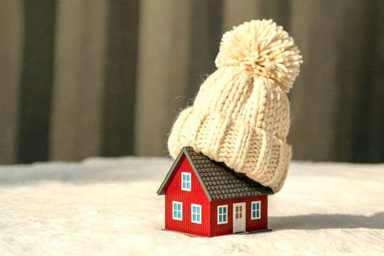 Mini Red House Wearing Winter Knitted Hat in Snow for Home Heating Concept - Powered by Adobe