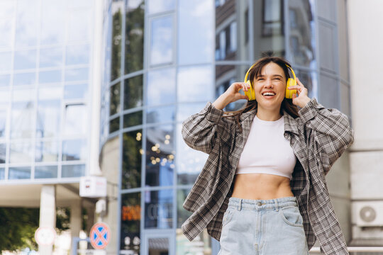 Happy woman enjoying music listening to yellow headphones