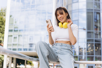 Young woman laughing holding smartphone in urban setting