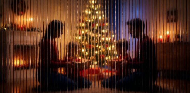 Silhouette of a family opening gifts by a Christmas tree behind ribbed glass. - Powered by Adobe