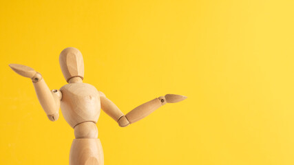 Wooden mannequin making a shrug gesture on yellow background