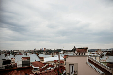 Atmospheric view over the red tile rooftops of historic Lviv, Ukraine, under a cloudy sky. A classic European urban landscape showcasing traditional architecture and chimneys.