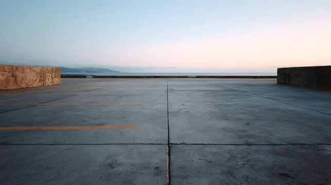 A serene concrete surface with parking lines facing the ocean at dusk