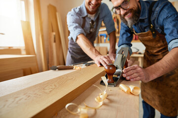 Carpenter anchors an oak plank at a busy workshop with skilled hands today.