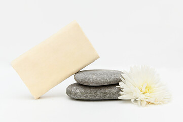 White handmade soap lies on pebbles. White flowers.