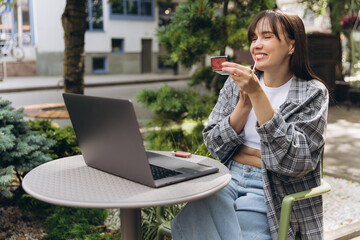 Young woman applying lip gloss at outdoor cafe