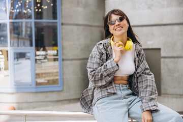 Fototapeta premium Young woman smiling with headphones in urban setting