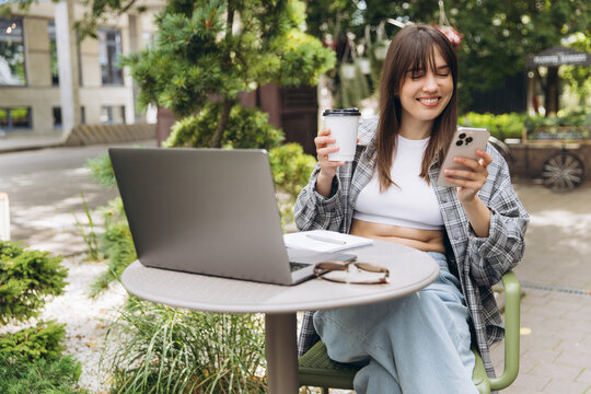 Woman working remotely at outdoor cafe using phone - Powered by Adobe