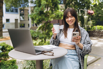 Woman working remotely outdoors using laptop and phone