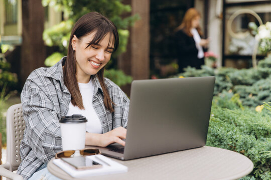 Young woman smiling working on laptop outdoors - Powered by Adobe
