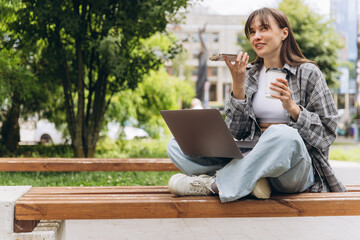 Woman working remotely on park bench talking on phone