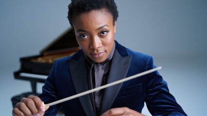 Close-up lead conductor faces front, baton poised, commanding stage presence