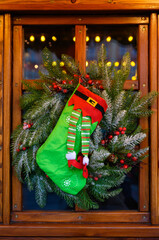 A cozy Christmas stocking displayed on a rustic window frame with greenery, ornaments, and glowing lights. Ideal for promotions, home decor brands, festive marketing materials, and Christmas designs.
