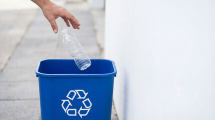 Hand Throwing Empty Plastic Water Bottle into Blue Recycling Bin