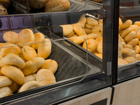 Abundant fresh baked bread rolls displayed in a modern self-service supermarket bakery section, offering daily choice for convenient grocery shopping