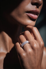 Close-up glamour shot of elegant hand wearing dazzling diamond ring, dramatic lighting highlighting luxury jewellery and refined texture.