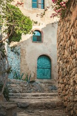 Old stone architecture featuring a medieval church, house, and wall with an arch, door, and window in an ancient European town alley