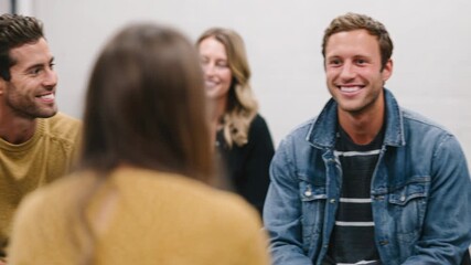 three people counseling session blue chairs smiling facilitator plant modern office casual clothing warm supportive atmosphere attentive listening peer