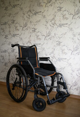 Vertical image of a wheelchair in a clean interior with a light patterned wall and wooden floor. Suitable for healthcare, rehabilitation, mobility assistance, accessibility themes, and medical service