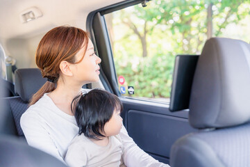 子どもと一緒にタクシーに乗って外を眺めるお母さん