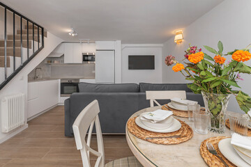 Round white lacquered beech table with Scandinavian-style chairs and a delicate bouquet of white lilies as a centerpiece