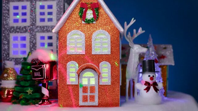 On a dark blue background, a Christmas town with colorful houses, snowmen, and Christmas trees next to them is rotating