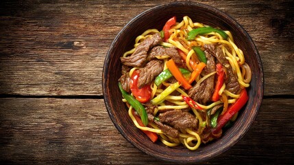 Top view of a Xinjiang Lagman traditional Uyghur noodle dish, hand-pulled noodles topped with stir-fried beef and vegetables bell peppers, tomatoes, carrots, onions, chili served in a rustic bowl