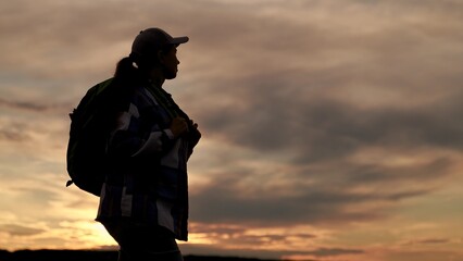 Hiker woman. Active tourist woman silhouette, traveling in nature against beautiful sky, closeup. Woman travel, freedom female backpacker trekking discovery contemplate picturesque sunrise cloudscape