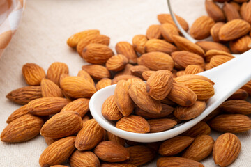 Dry roasted Almonds in white spoon on wooden table.Heap of almond