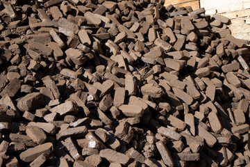 A large stack of peat briquettes is shown, prepared for eco-friendly heating solutions in homes and industries