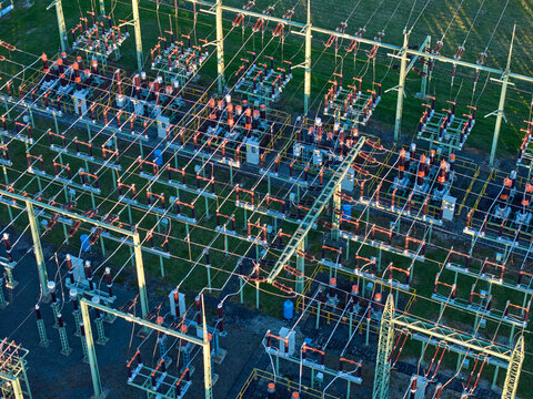 Aerial view of high-voltage electrical substation switchyard, energy infrastructure, complex grid infrastructure with insulators and lines.